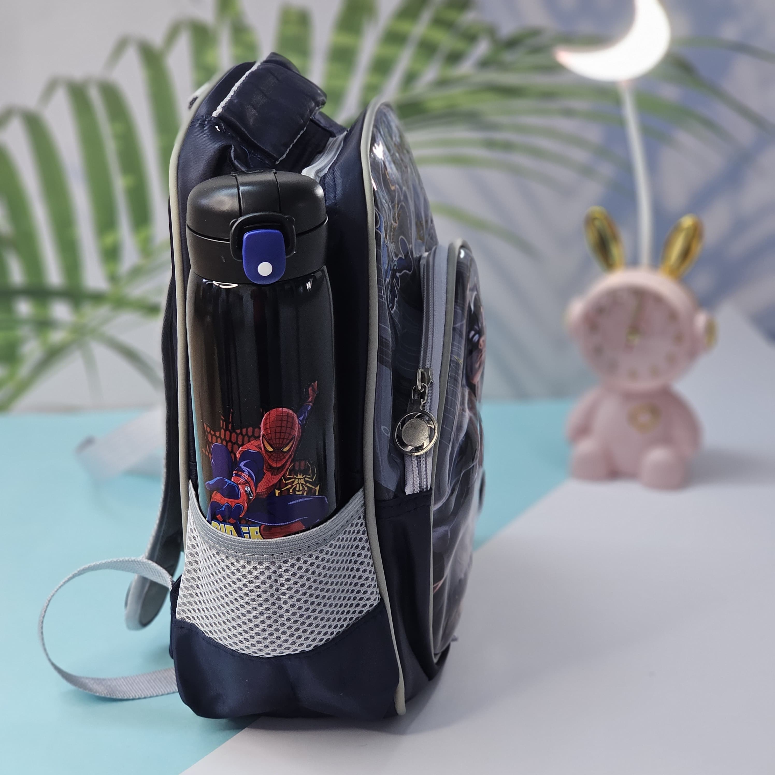 Backpack with water bottle holder featuring Spider-Man design on a light blue surface.